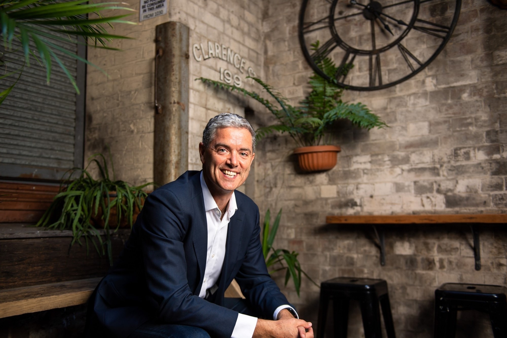 A man in a suit smiles while sitting