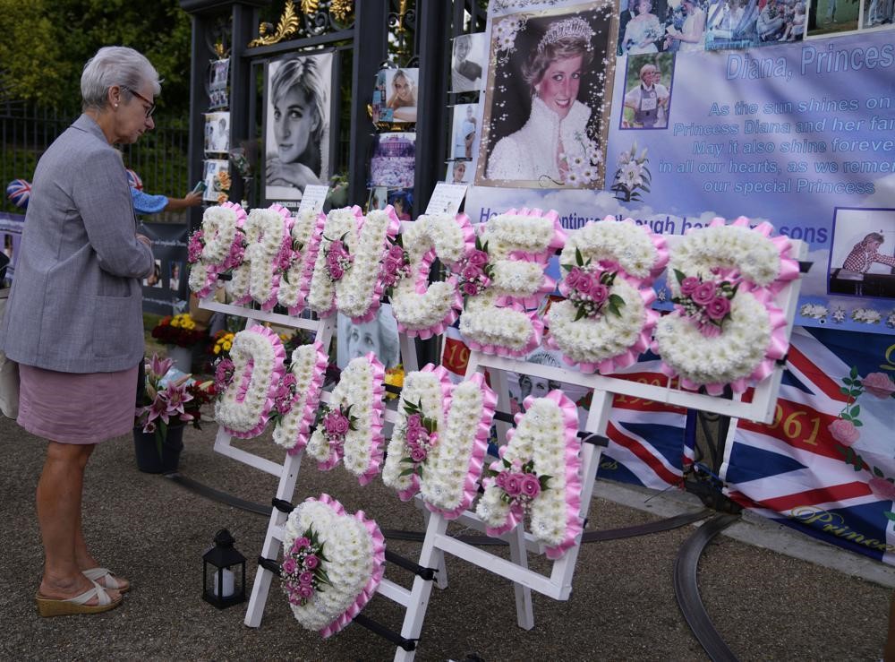 A woman looks at a flower arrangement that spells out Princess Diana.