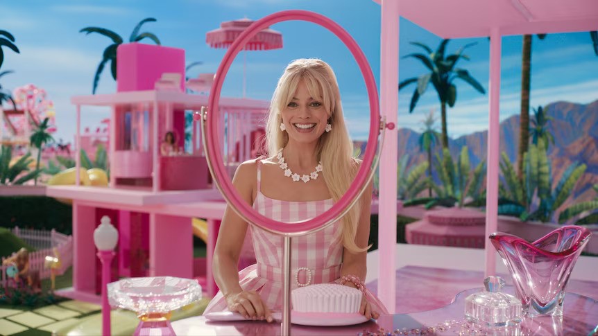 An image from the film Barbie of a blonde pretty lady that looks much like the doll.