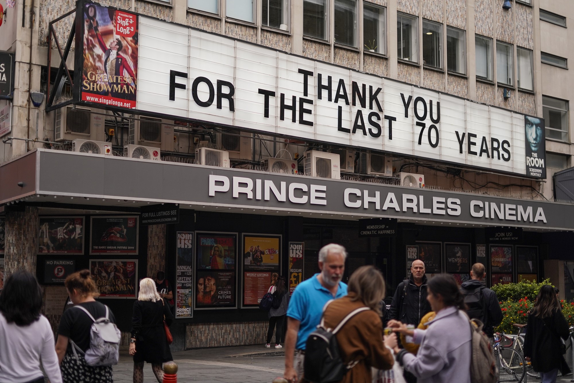 People walks past Prince Charles Cinema, which displays a message reading 'Thank you for the last 70 years', in Soho, in London