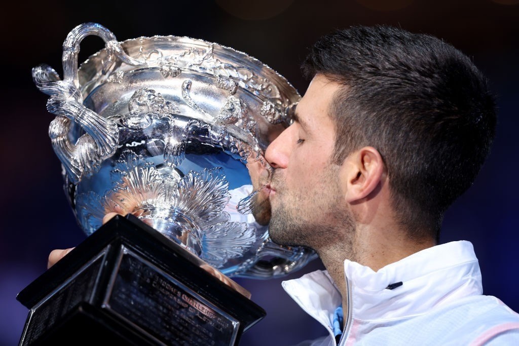 A man kisses a silver trophy.