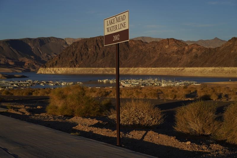 A sign says Lake Mead Water Line 2002 with the drought-stricken lake in the background.