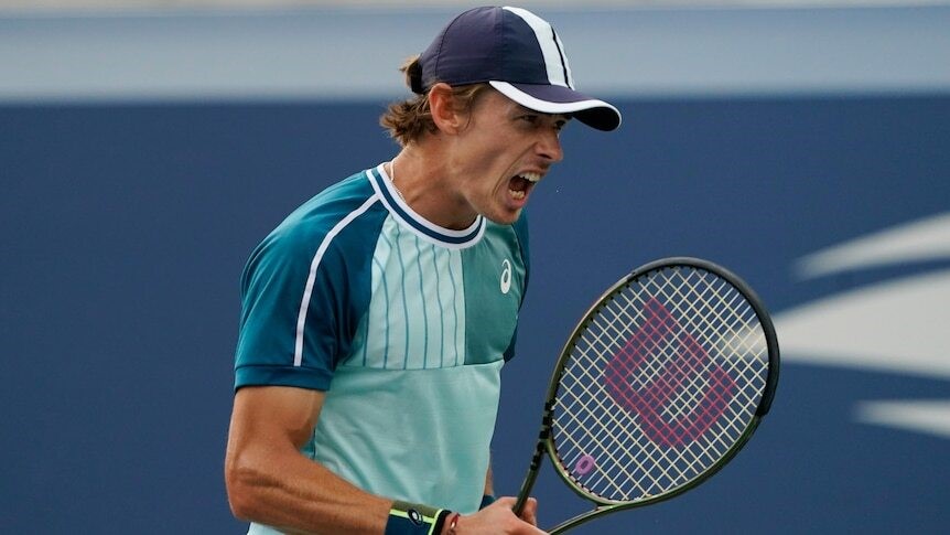 Alex screams on the court as he holds his racket.