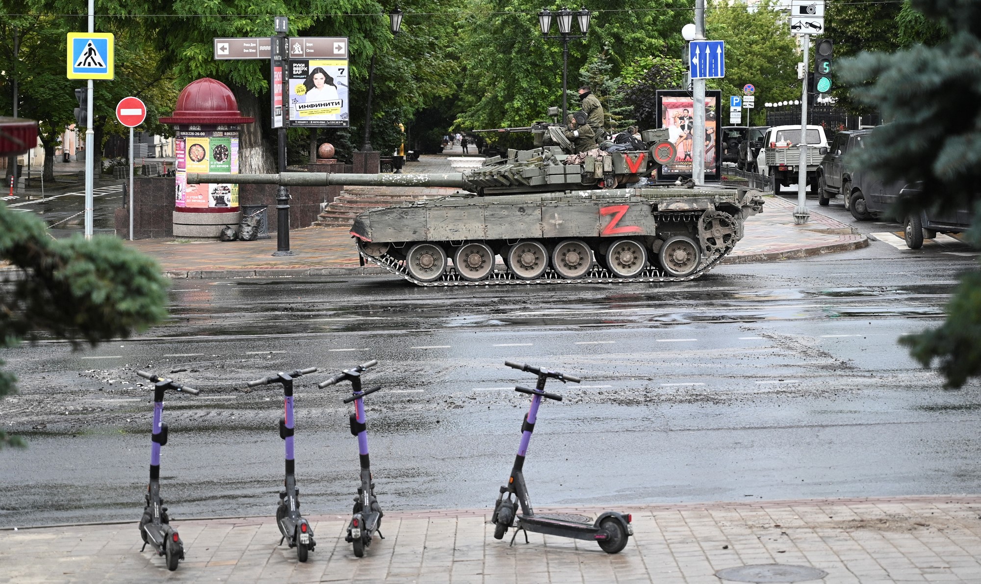 Electric scooters are parked on the kerb across the road from a tank on Rostov-on-Don