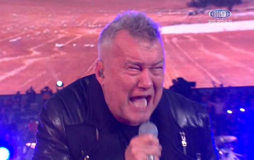 Jimmy Barnes screams into a microphone with a pained expression on his face.