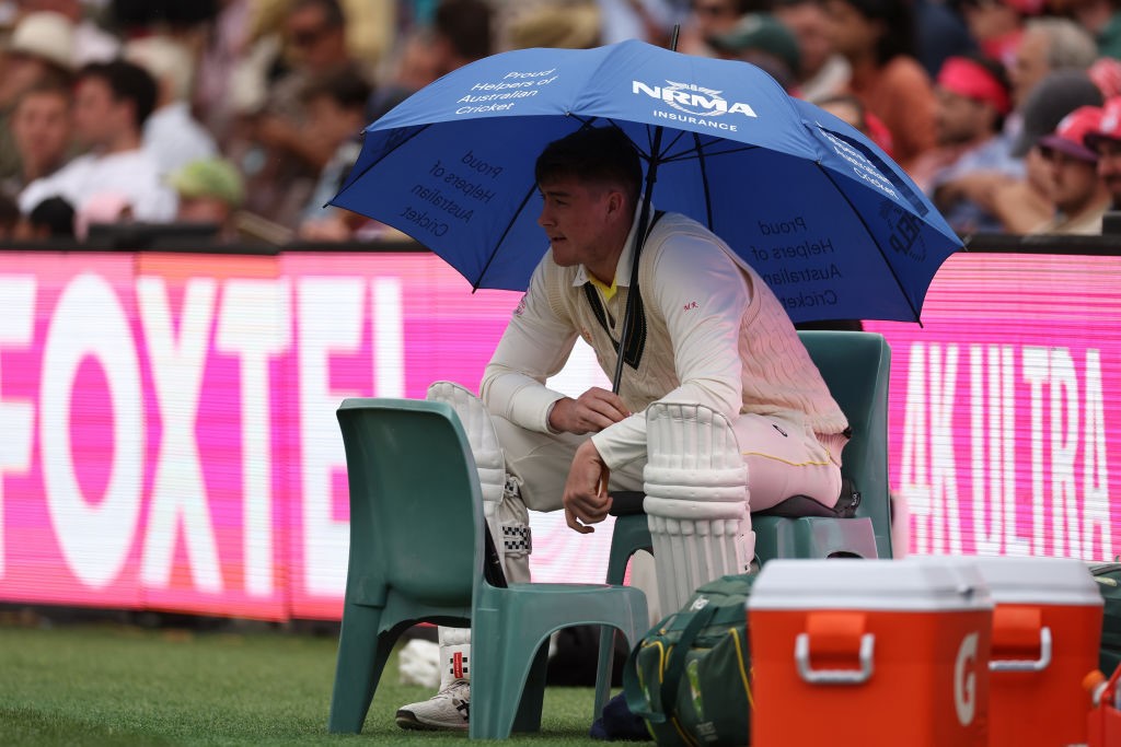 Australia batter Matt Renshaw sits under an umbrella in his whites on the boundary at the SCG Test.