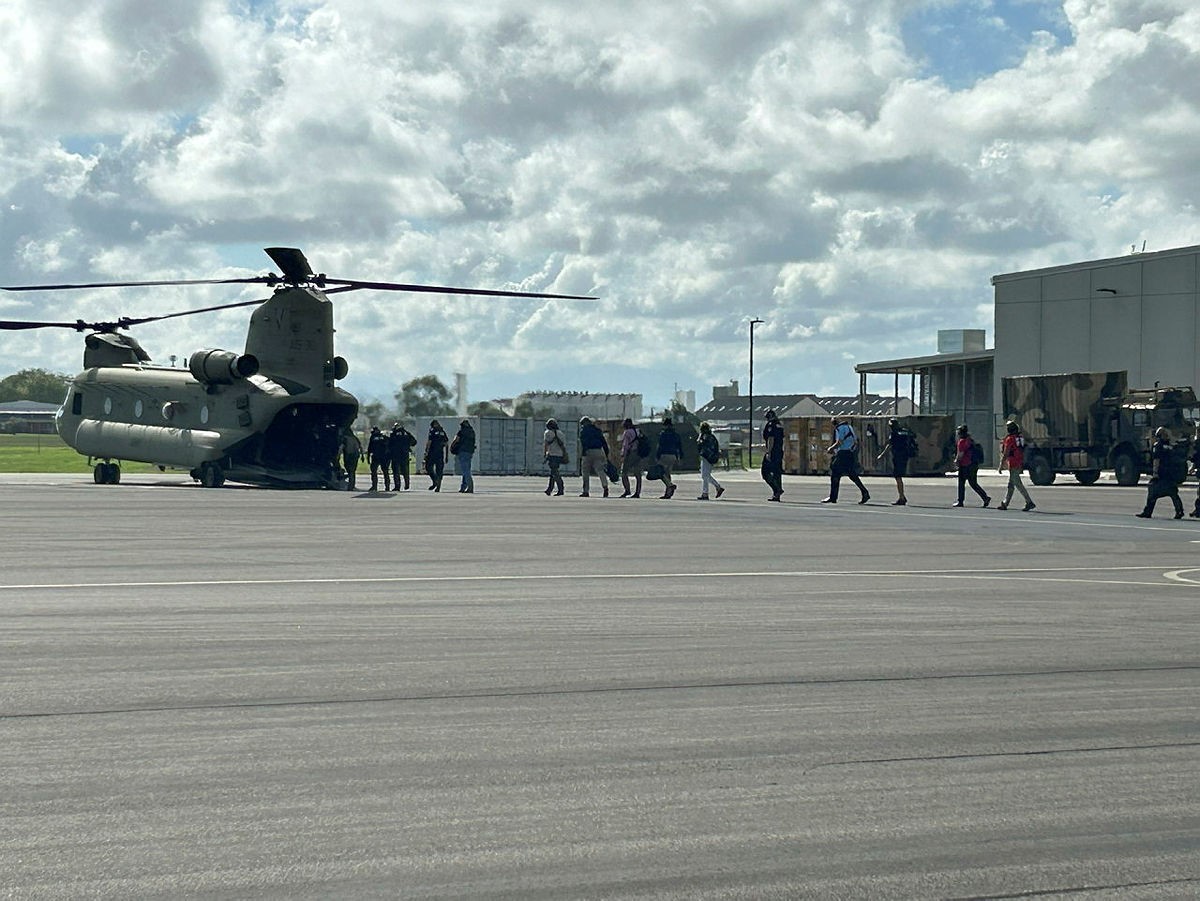 a line of crews board a chinook helicopter on a runway