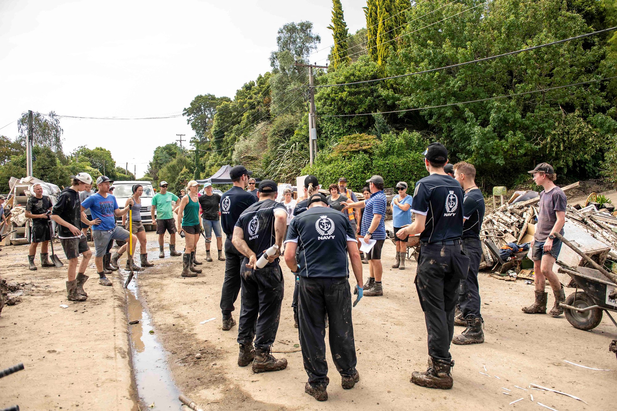 HMNZS Te Mana crew members help with a clean up after a small creek bursts its bank causing houses to flood in Havelock North, New Zealand