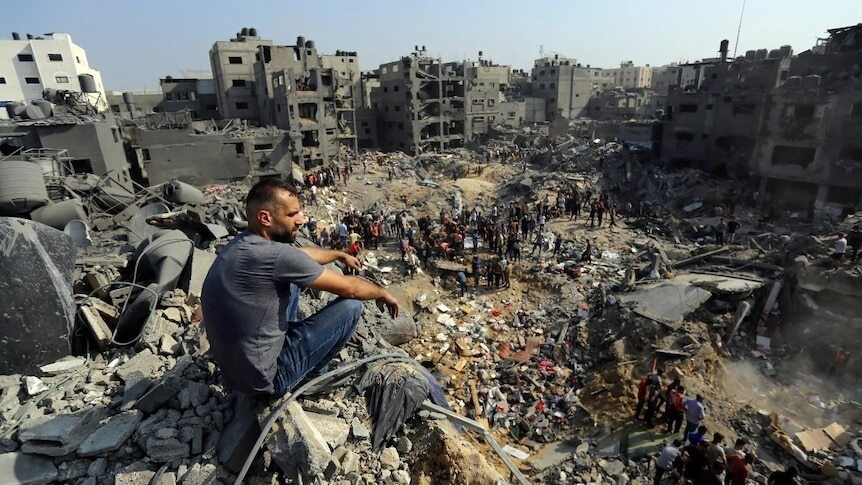 A man sits and observes the destruction of a Gaza refugee camp.
