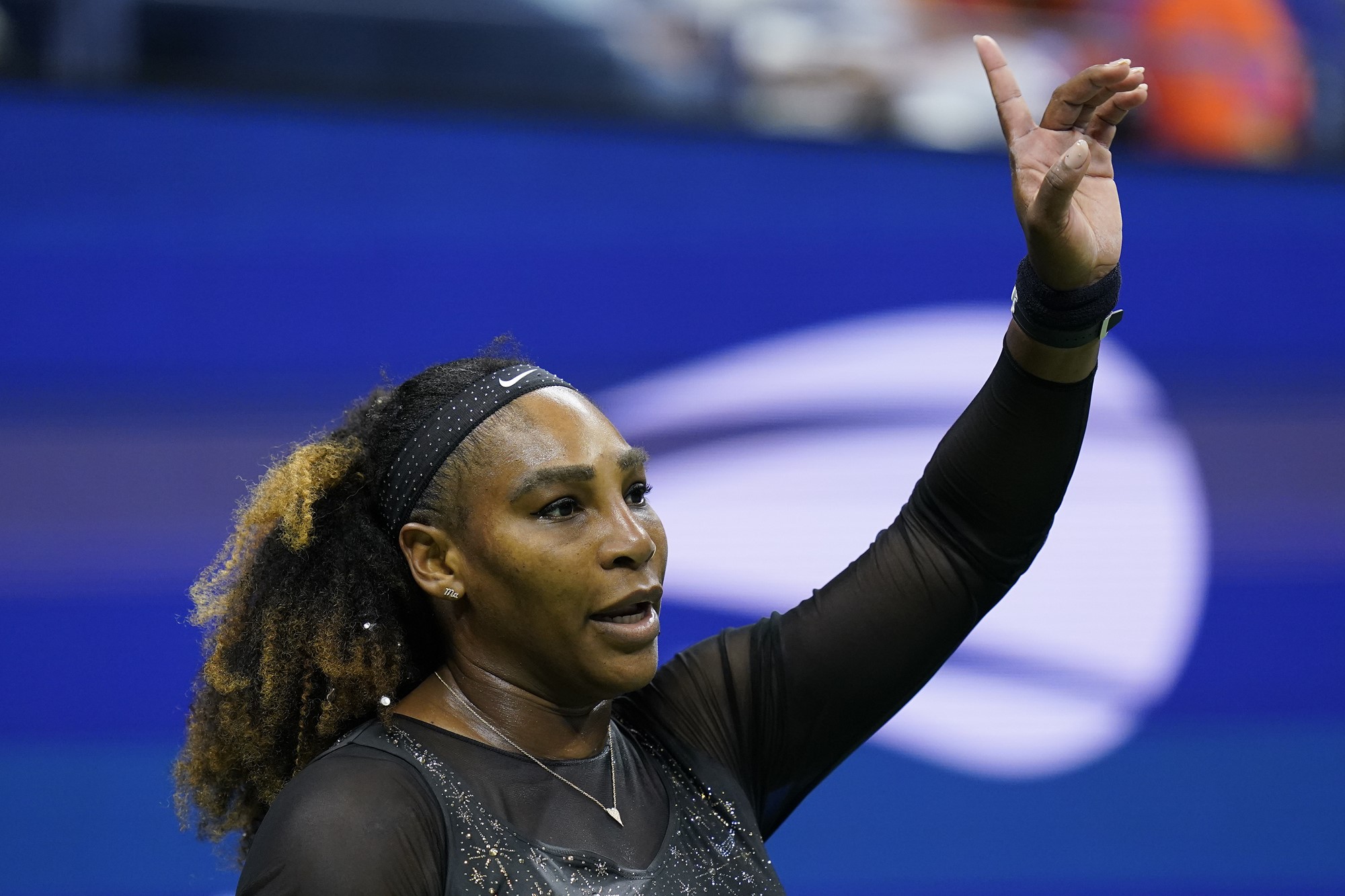 A woman in all black raises her hand.