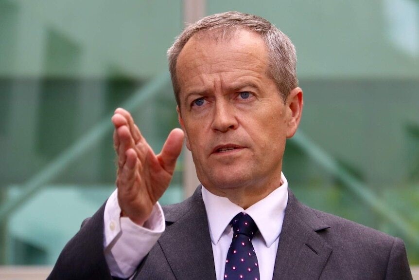 A close up of Shorten gesturing with his right hand outside parliament as he speaks.