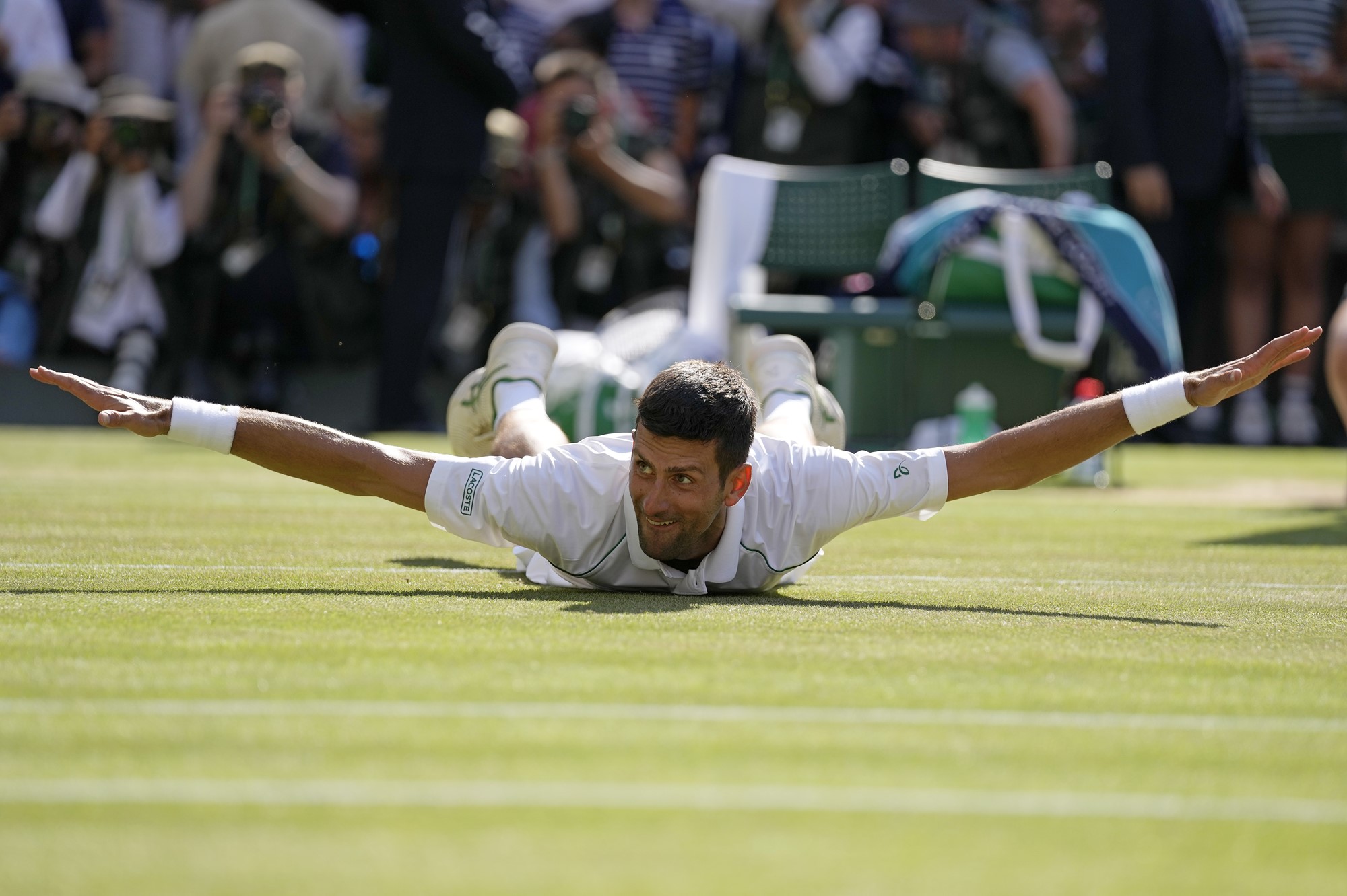 Novak Djokovic lies on his stomach with his arms outstretched after the Wimbledon final.