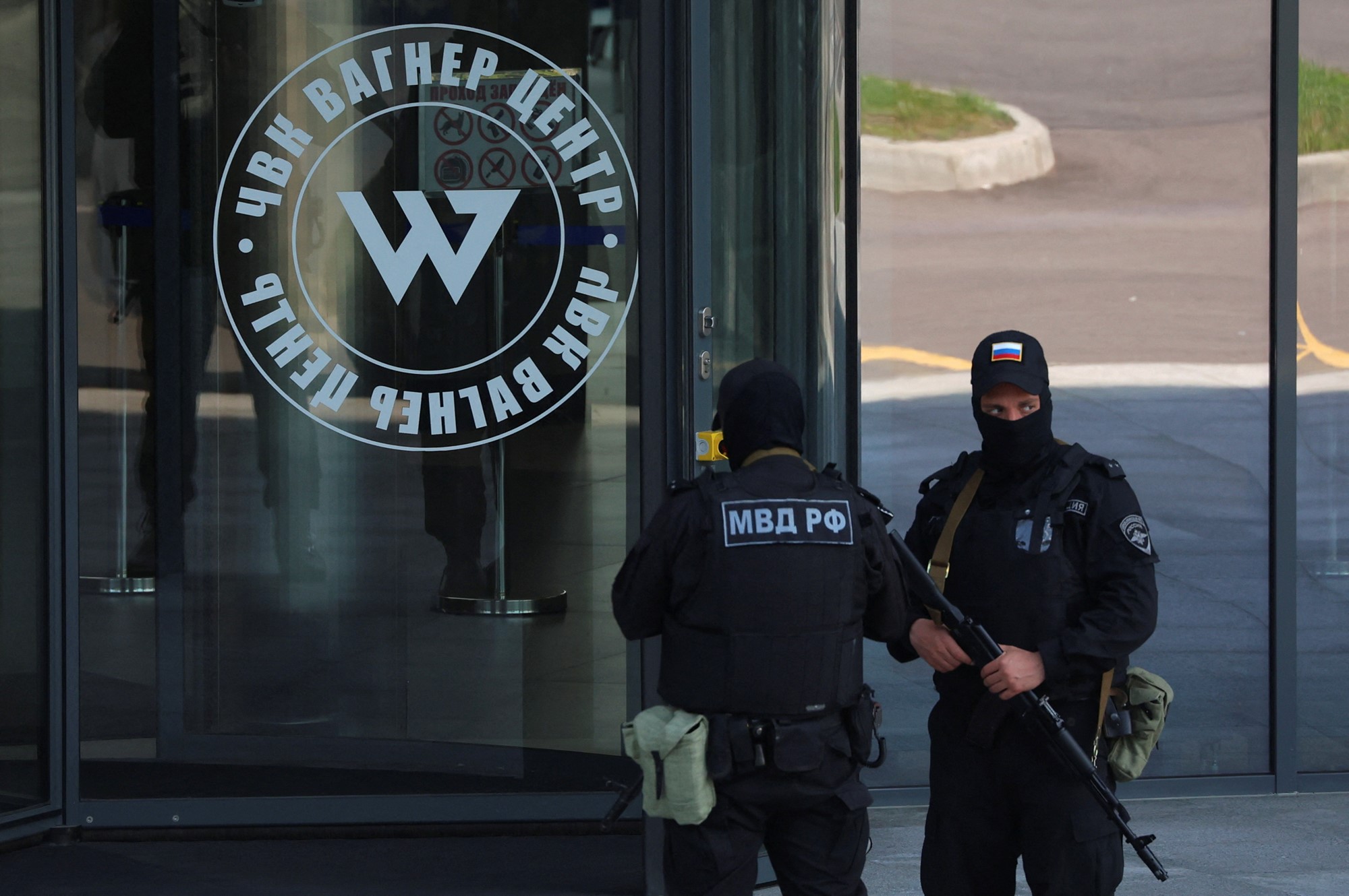 Two armed police stand outside a building with the Wagner logo on its glass walls