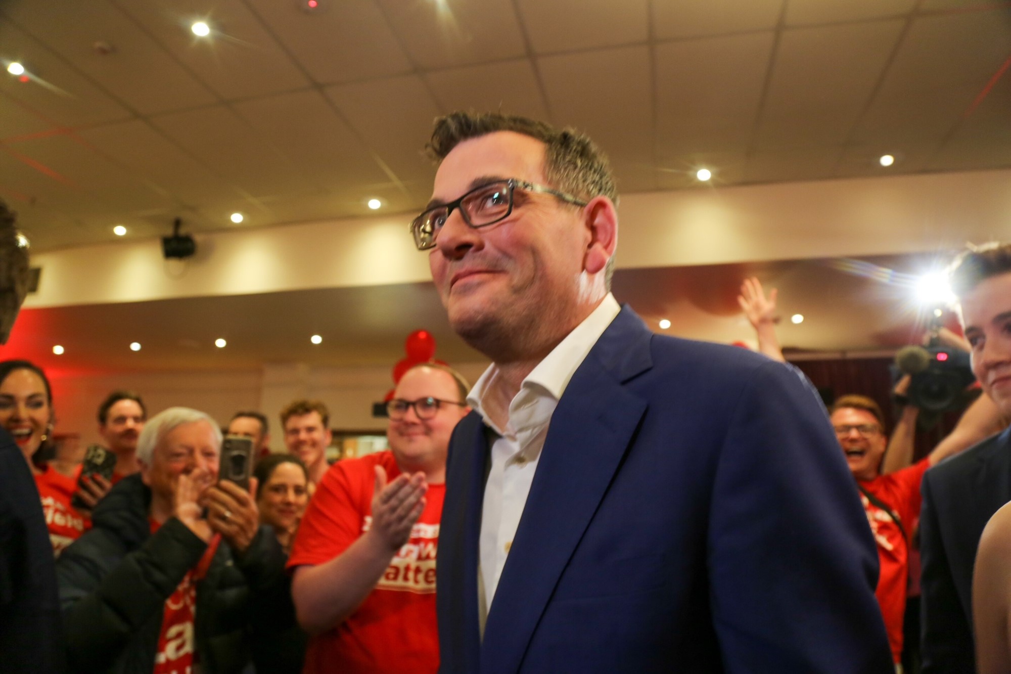 Daniel Andrews smiling, with Labor supporters behind him.