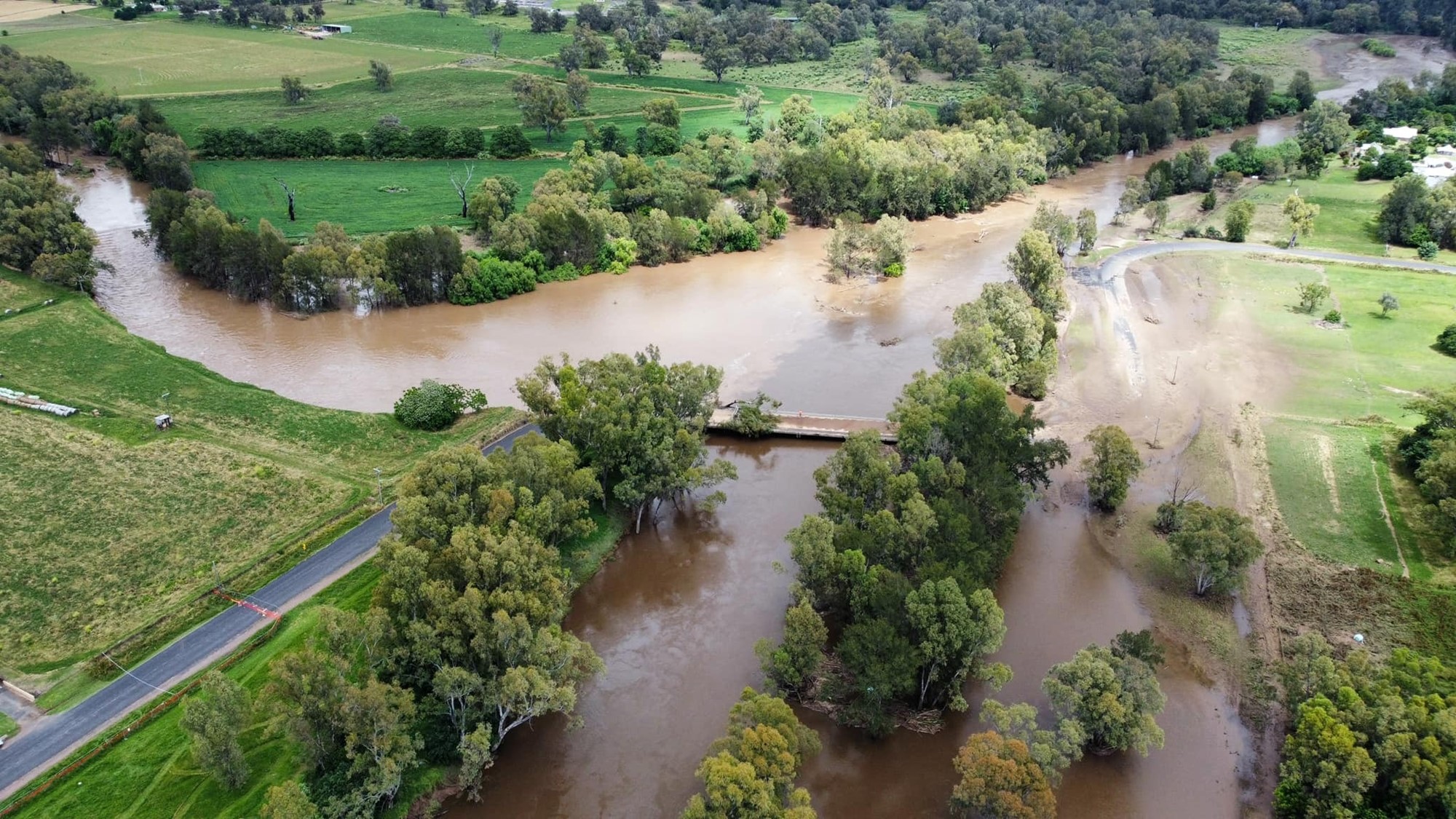 Photo shows an aerial view of a flooded road.