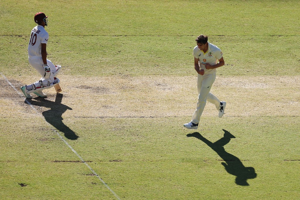 Pat Cummins runs past Roston Chase after taking his wicket.