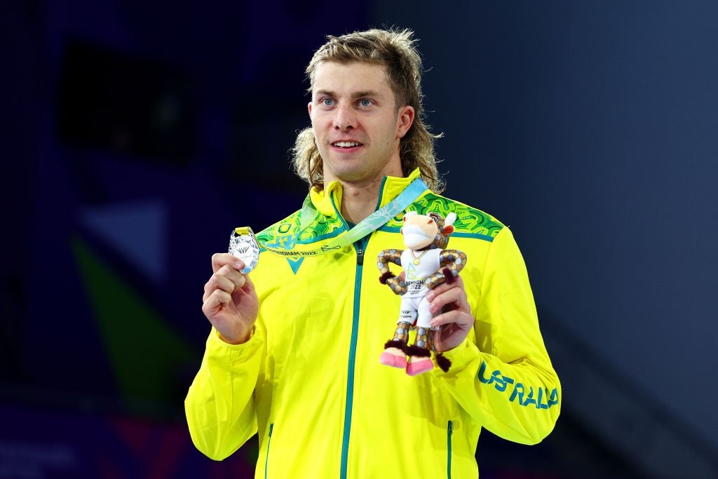 Matthew templeton poses on podium with medal and small toy mascot