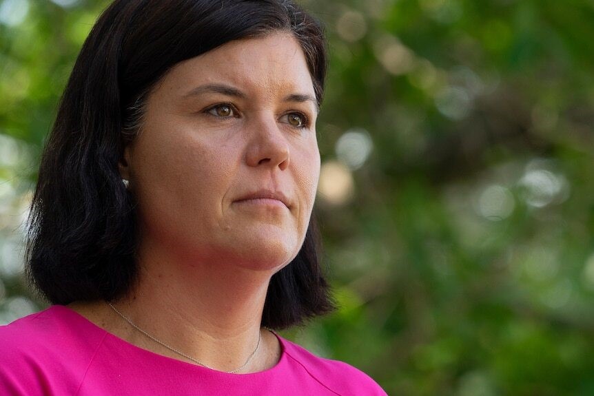 A close up of Natasha looking into the distance while wearing a hot pink top.