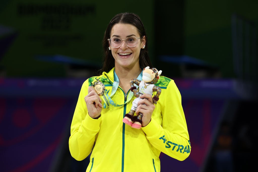 kaylee mckeown smiles and holds her medal and toy on podium