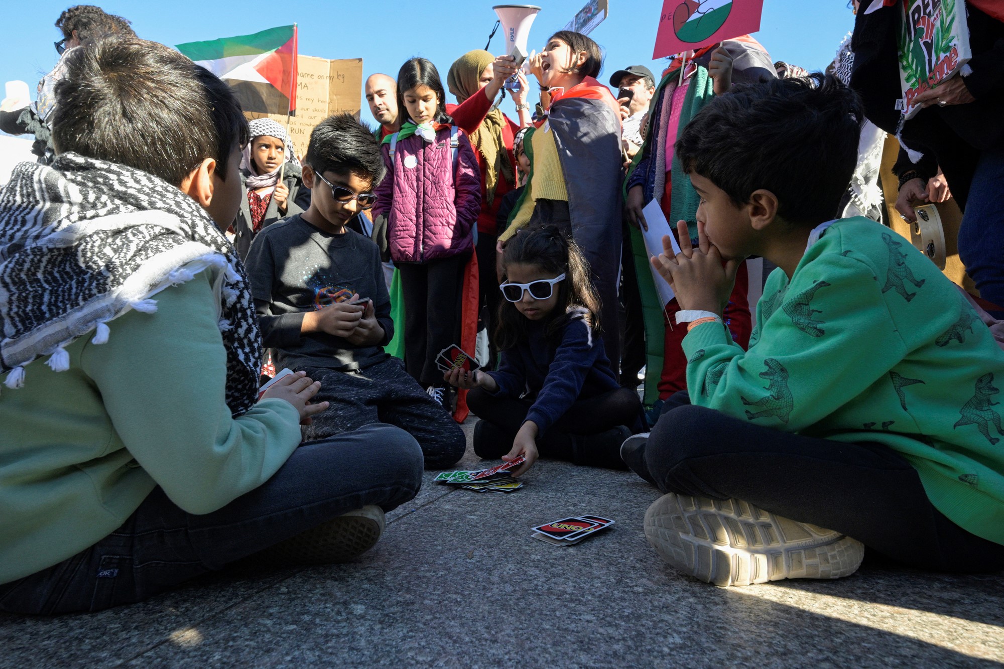 Children sit on the ground playing uno