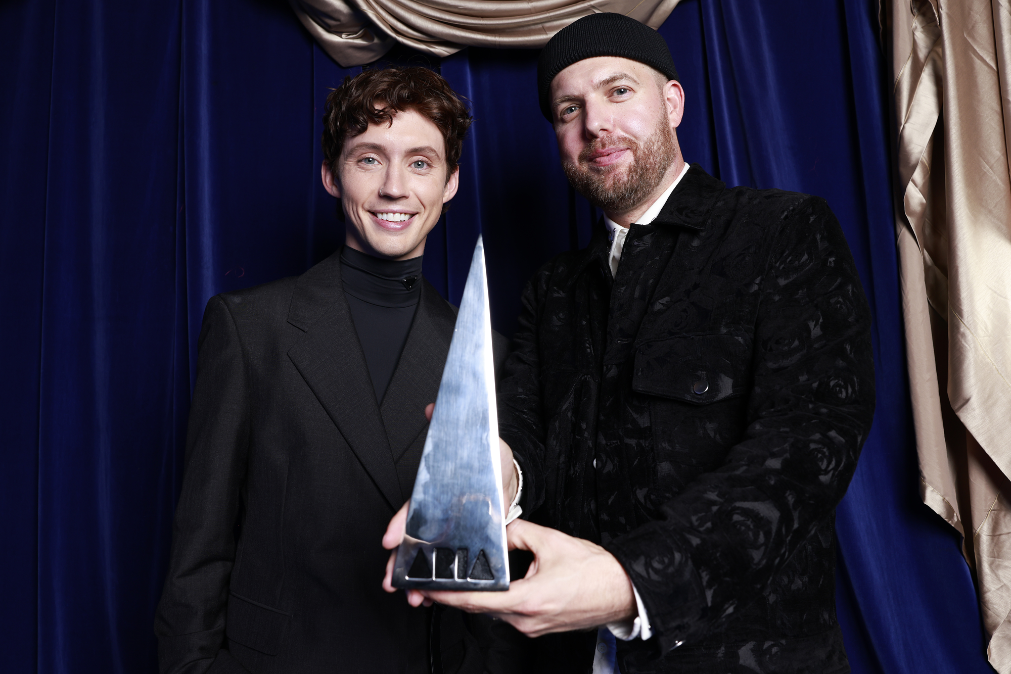 Styalz Fuego (R) poses with Troye Sivan holding an Aria