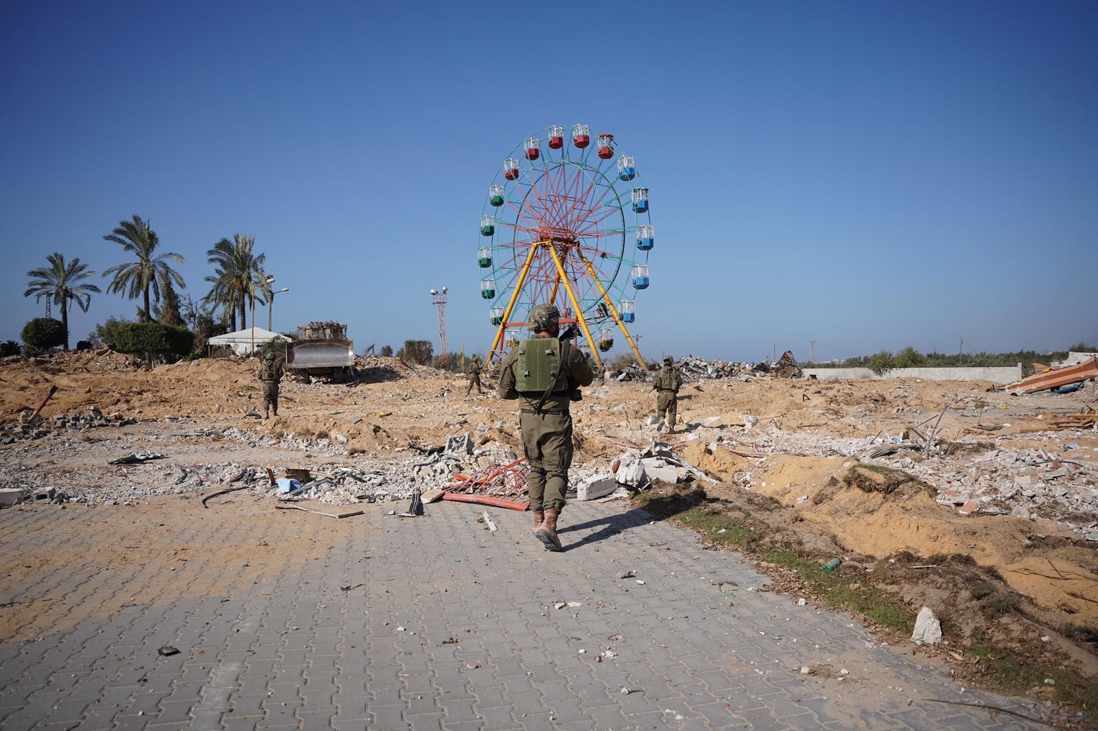 A soldier standing in an arid area, with a ferris wheel in the distance