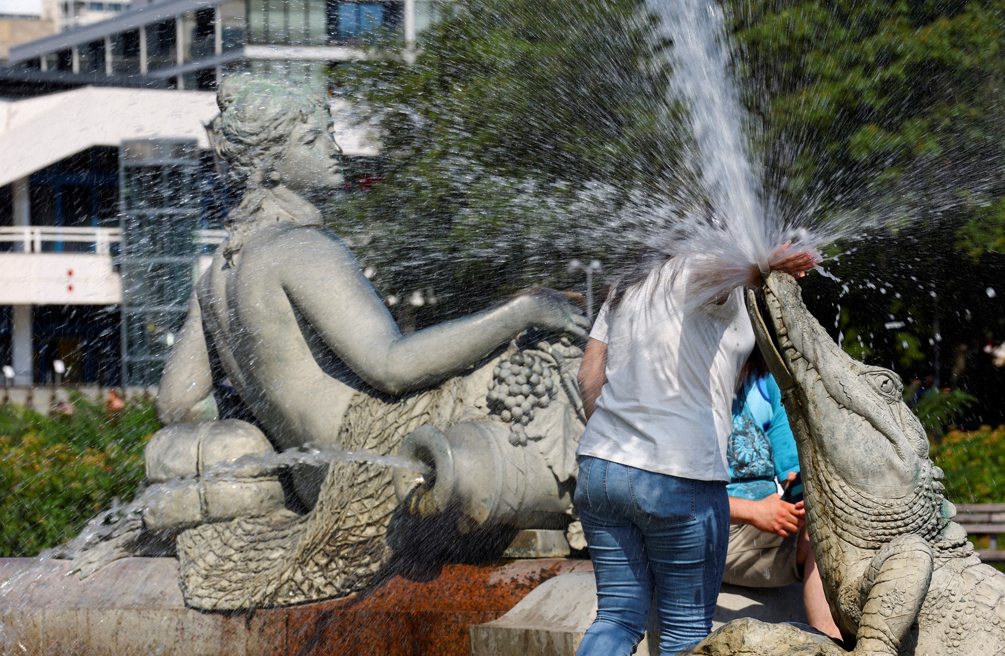 A person cools off in Neptune Fountain in Berlin.