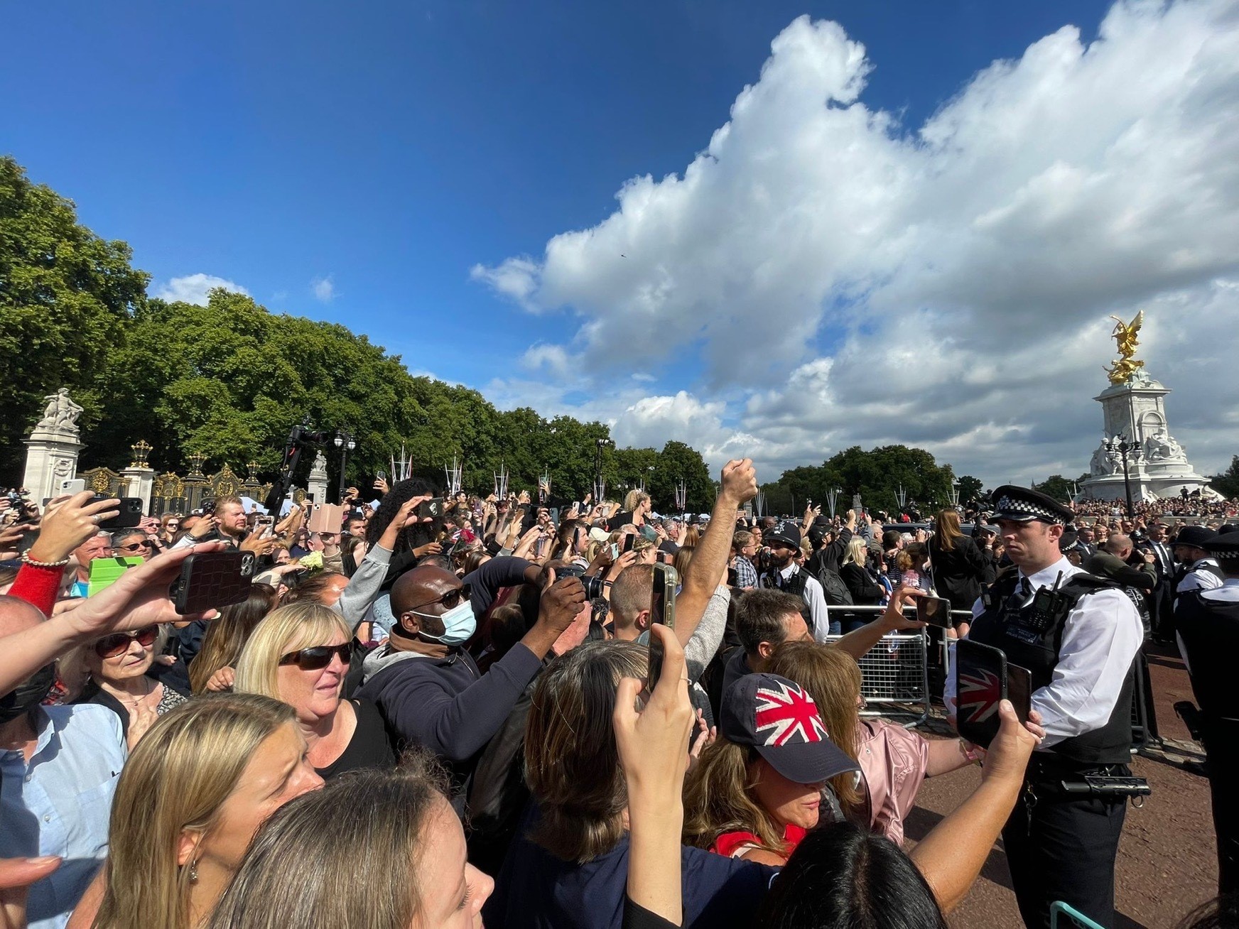 Crowds of mouners hold up smartphones outside of Buckingham Palace