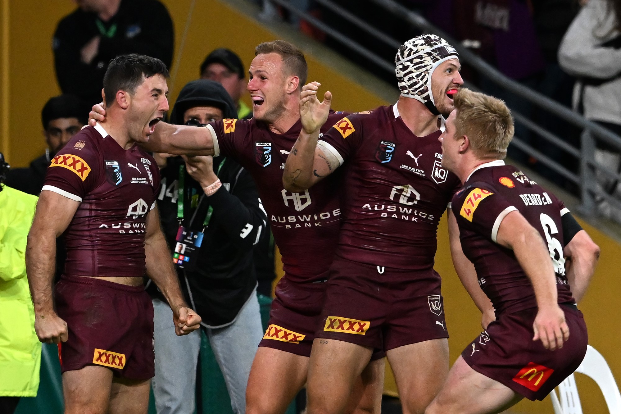 Ben Hunt (left) shouts as he is embraced by Queensland Maroons teammates after a State of Origin try.