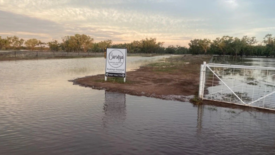 A sign for Carinya Station surrounded by floodwater