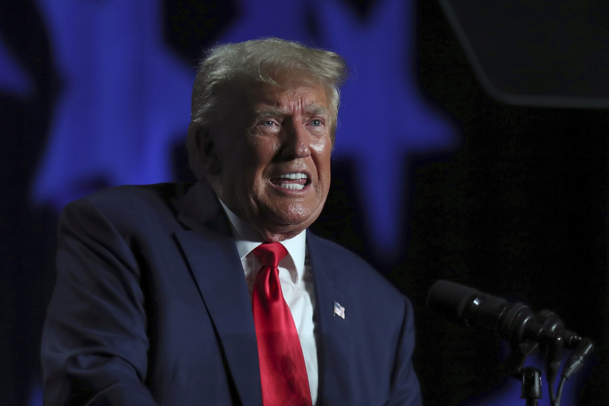 Donald Trump speaking at a lecturn in a suit and tie