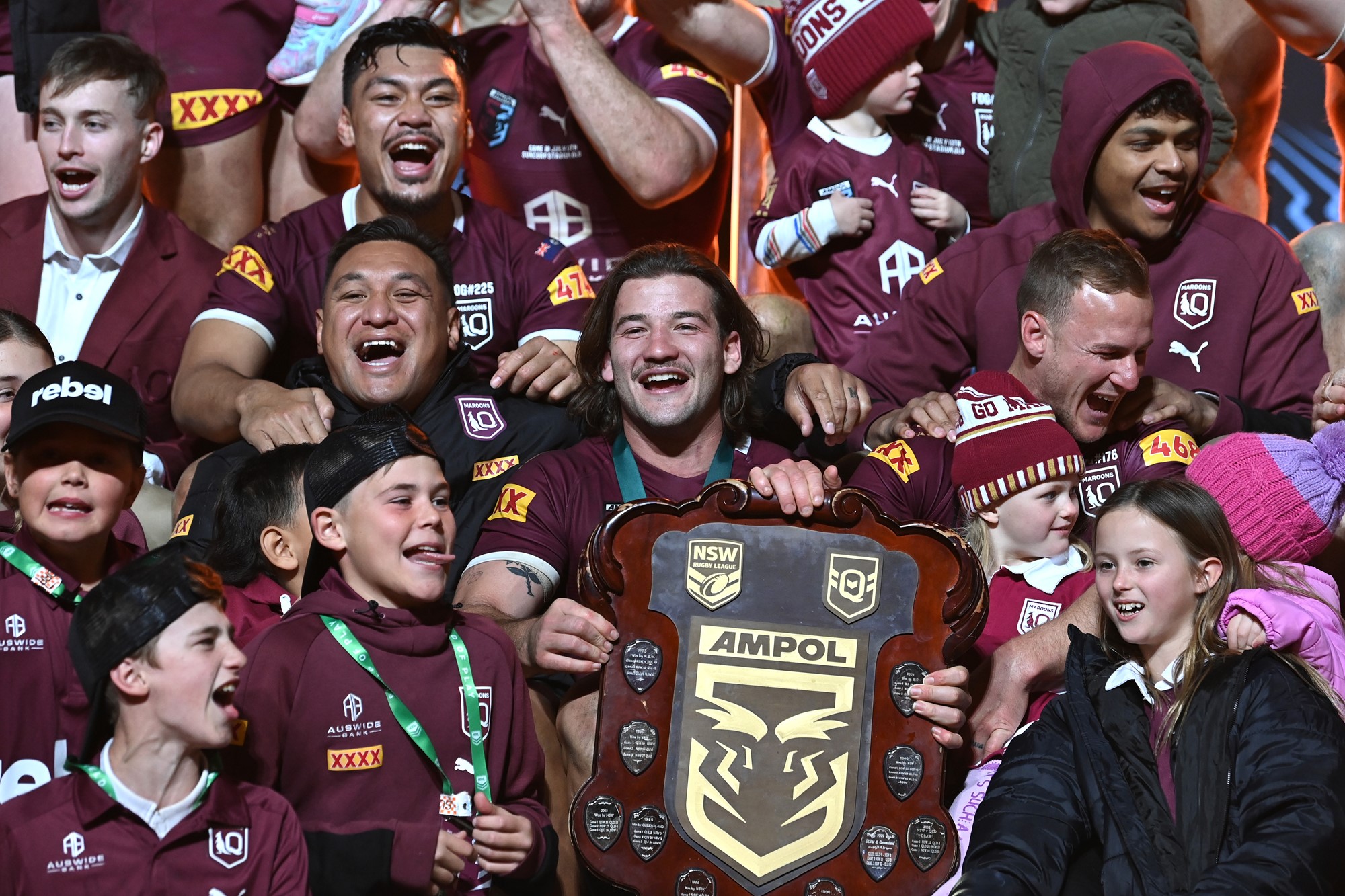 Patrick Carrigan holds the State of Origin while celebrating with Queensland Maroons teammates.