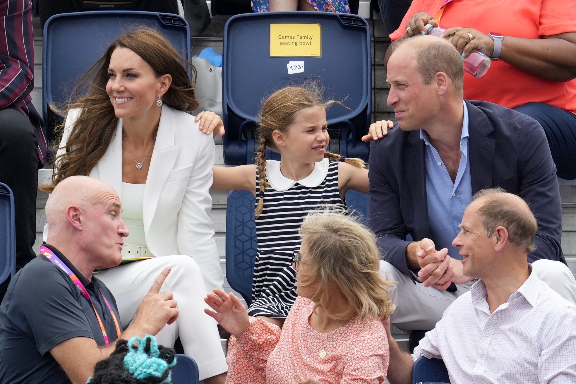 Britain's Princess Charlotte, centre, rests her hands on her parents, Kate, Duchess of Cambridge, background left and Prince William as they watch a hockey event, at the University of Birmingham Hockey and Squash Centre