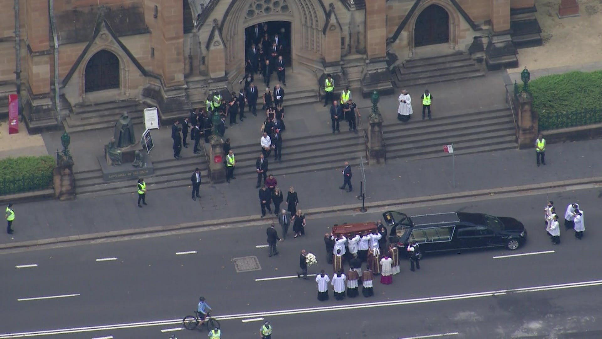 Aerial view of a coffin being lifted into a hearse