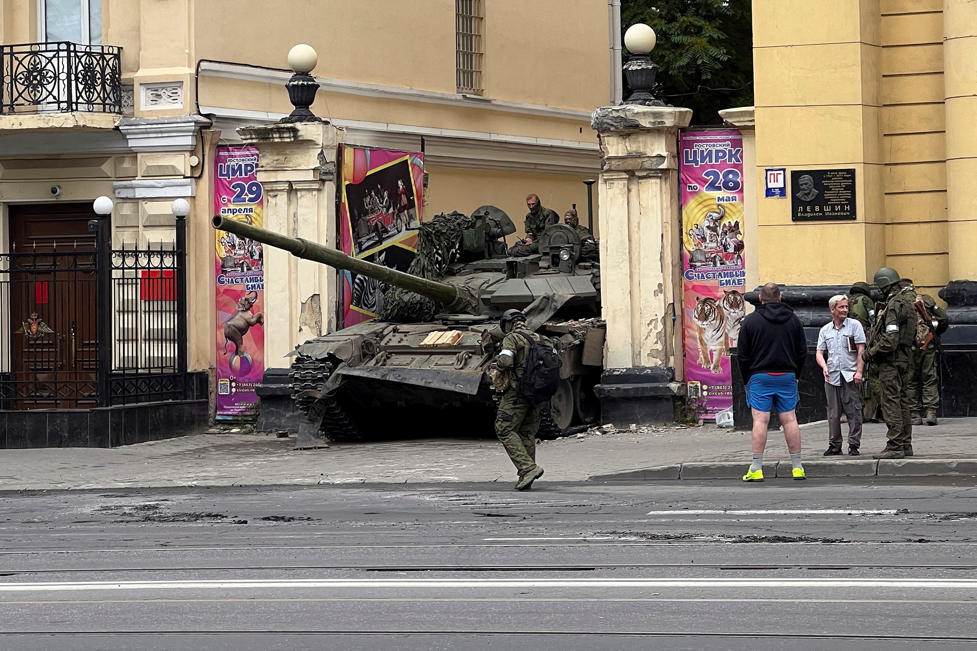 A tank with soldiers seen on a street. 