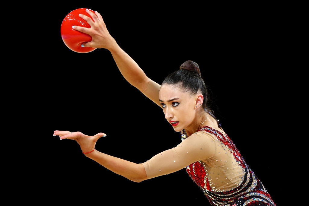 A rhythmic gymnast holds a red ball during a routine at the Commonwealth Games.