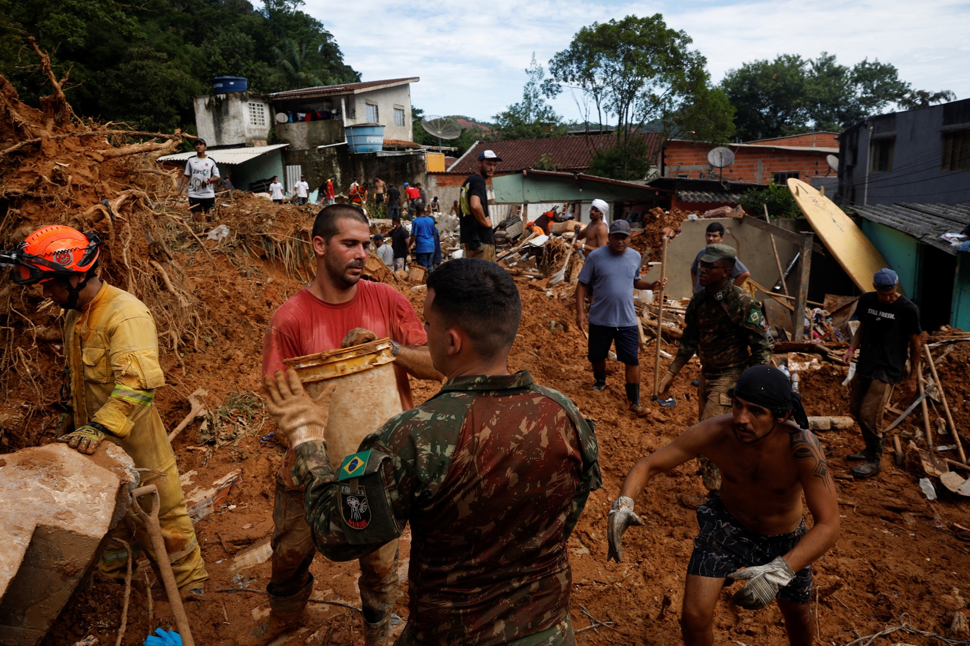 People walk through thick mud and rubble. 