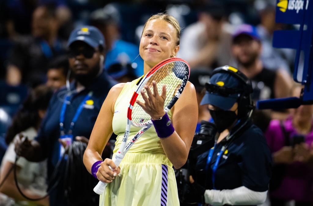 Anett Kontaveit smiles and claps her hand to her racquet