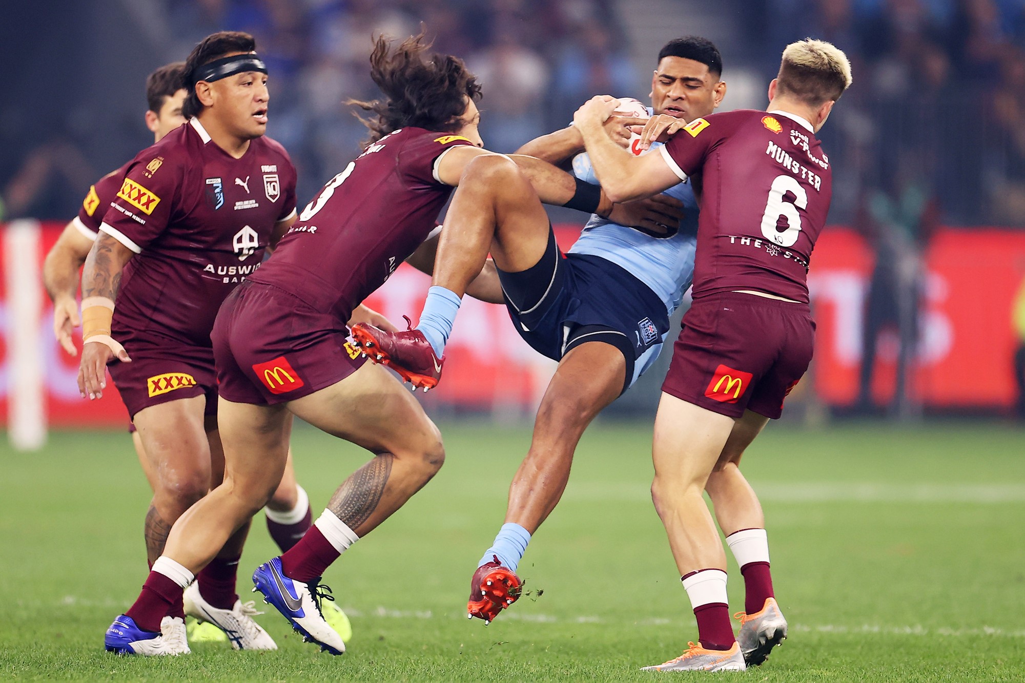 NSW Blues player Daniel Tupou is tackled by Cameron Munster and Tino Fa'asuamaleaui of the Queensland Maroons.