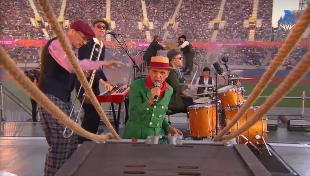 Un hombre vestido con un atuendo único canta en un micrófono.