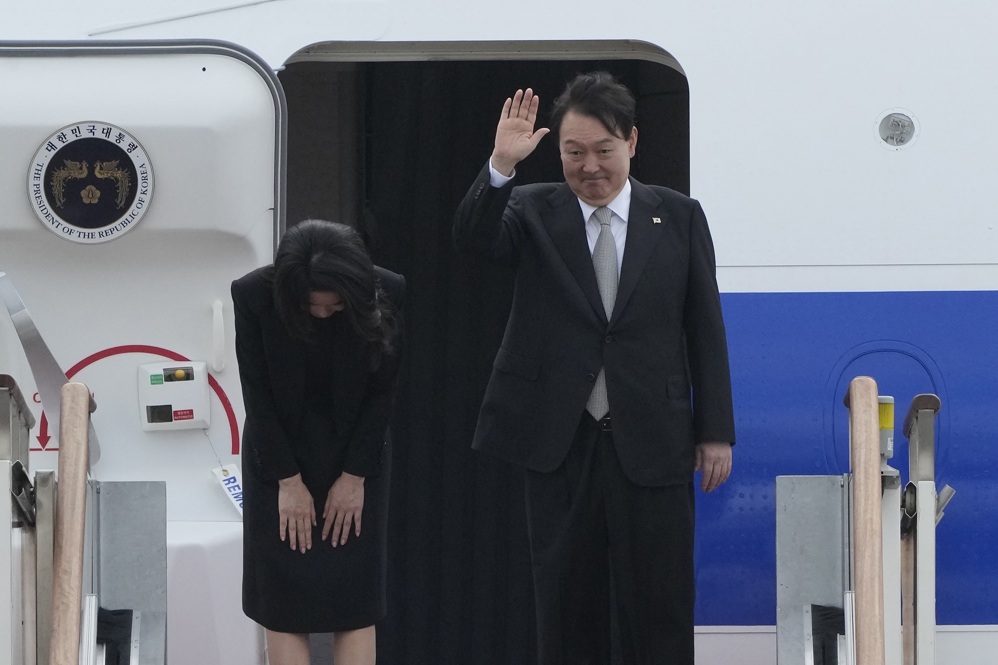 South Korean President Yoon Suk Yeol waves as his wife Kim Keon Hee bows 