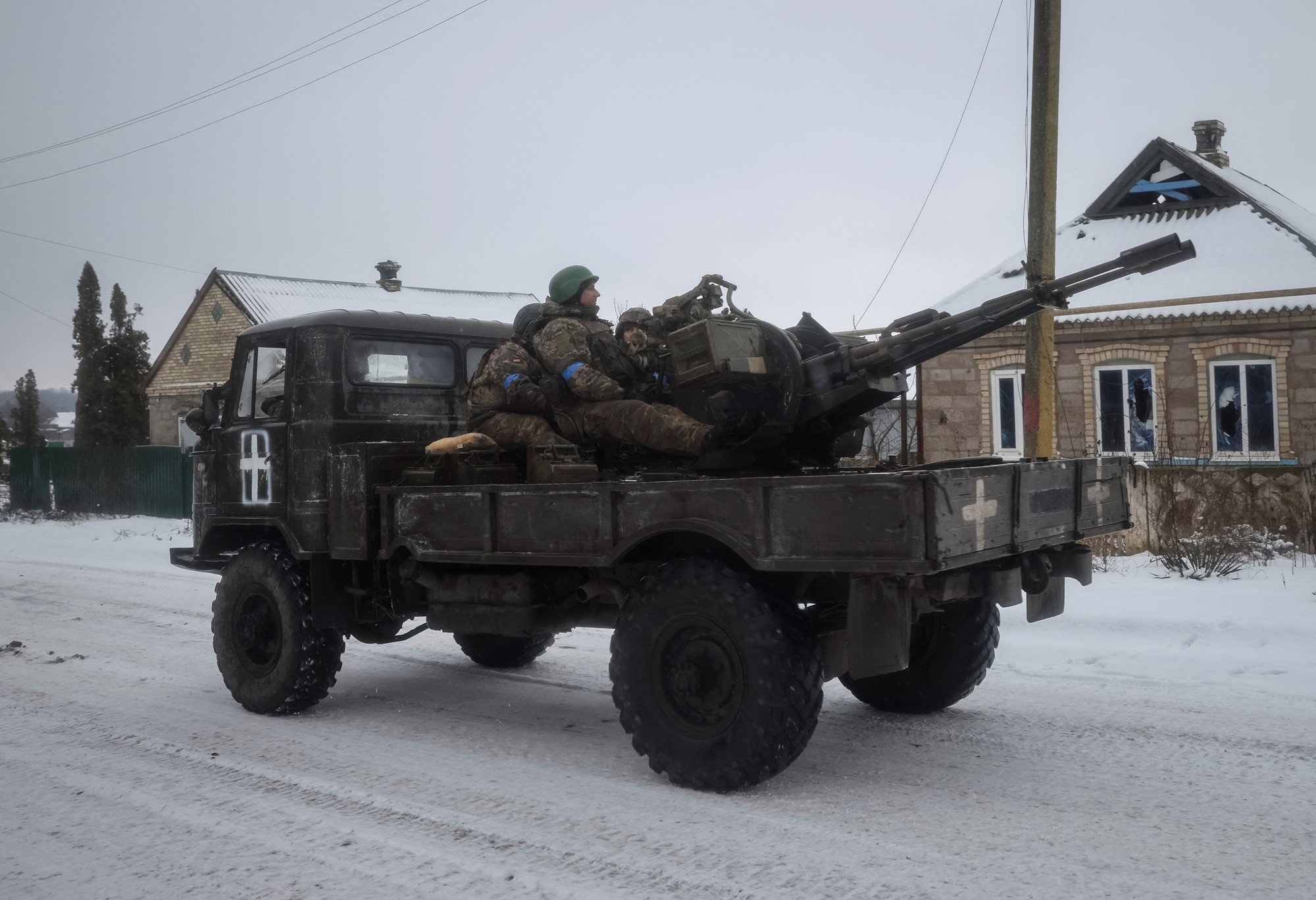 Ukrainian servicemen ride on a military vehicle with a ZU-23-2 anti-aircraft cannon.