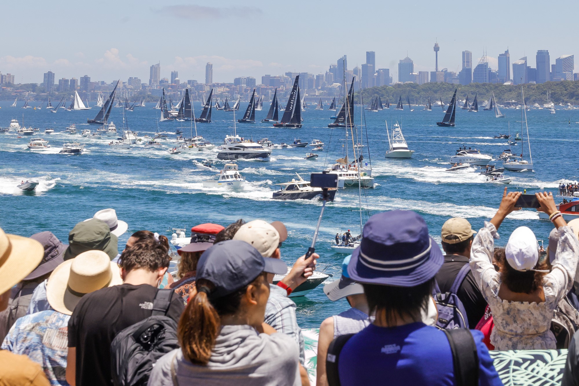 Spectators watch on and take photos of the fleet in the Sydney to Hobart yacht race.