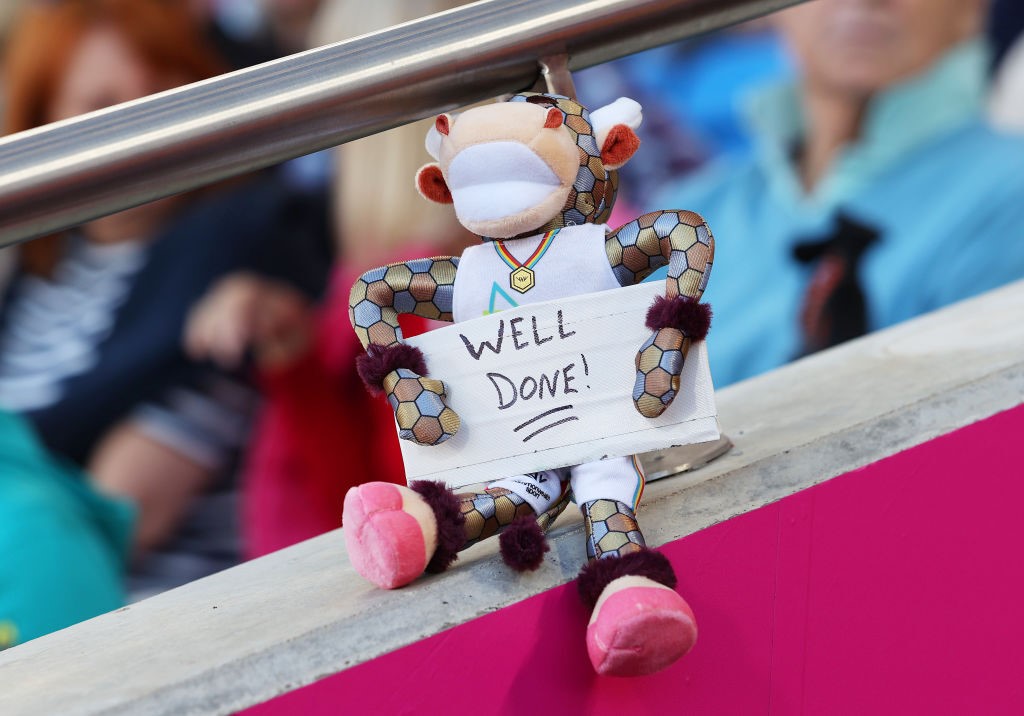 A stuffed cow holds a sign saying 'Well done'