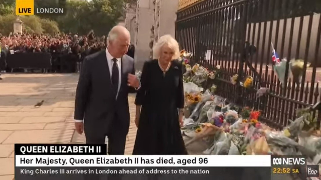 King Charles III and his wife Camilla inspect floral tributes.