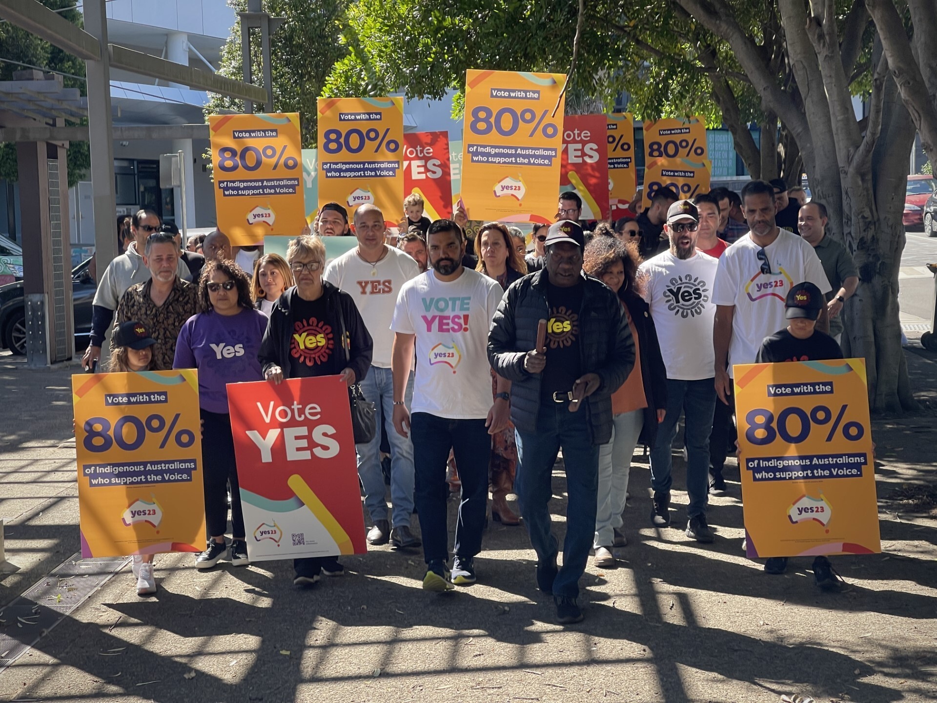 A Yes rally walks the street holding Vote Yes signs.