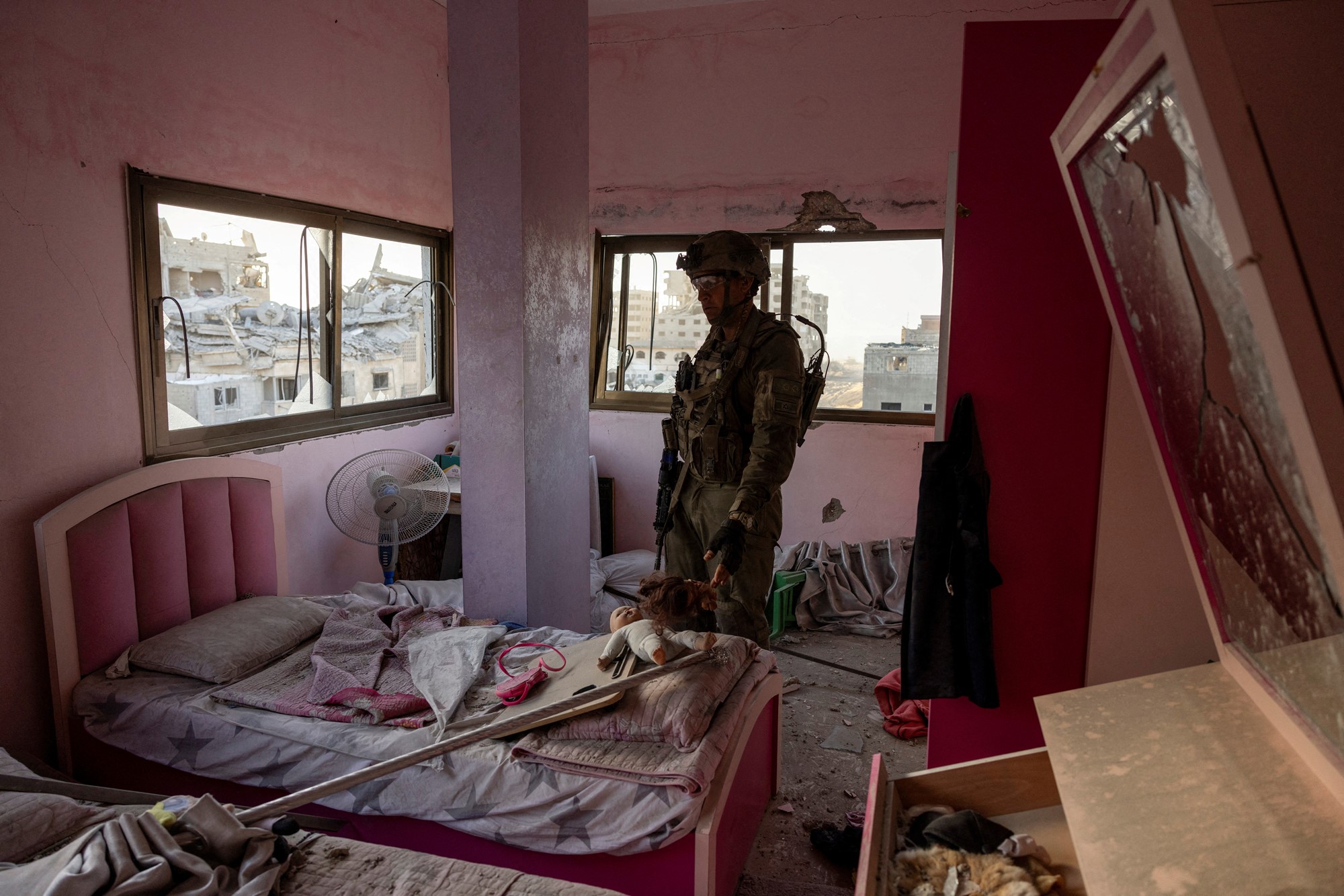 A man in army attire is standing in what looks like a child's pink bedroom.