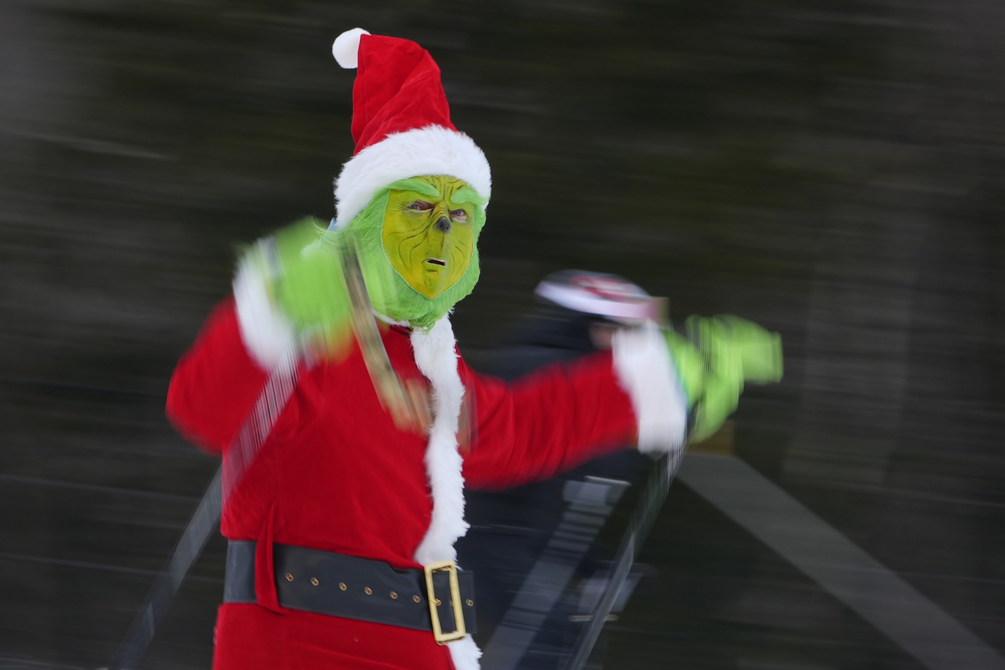 A person in a grinch costume skis down a hill.