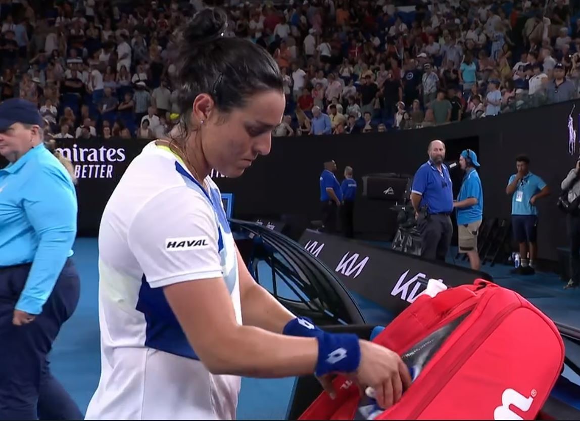 A teenis player puts her racket in a bag