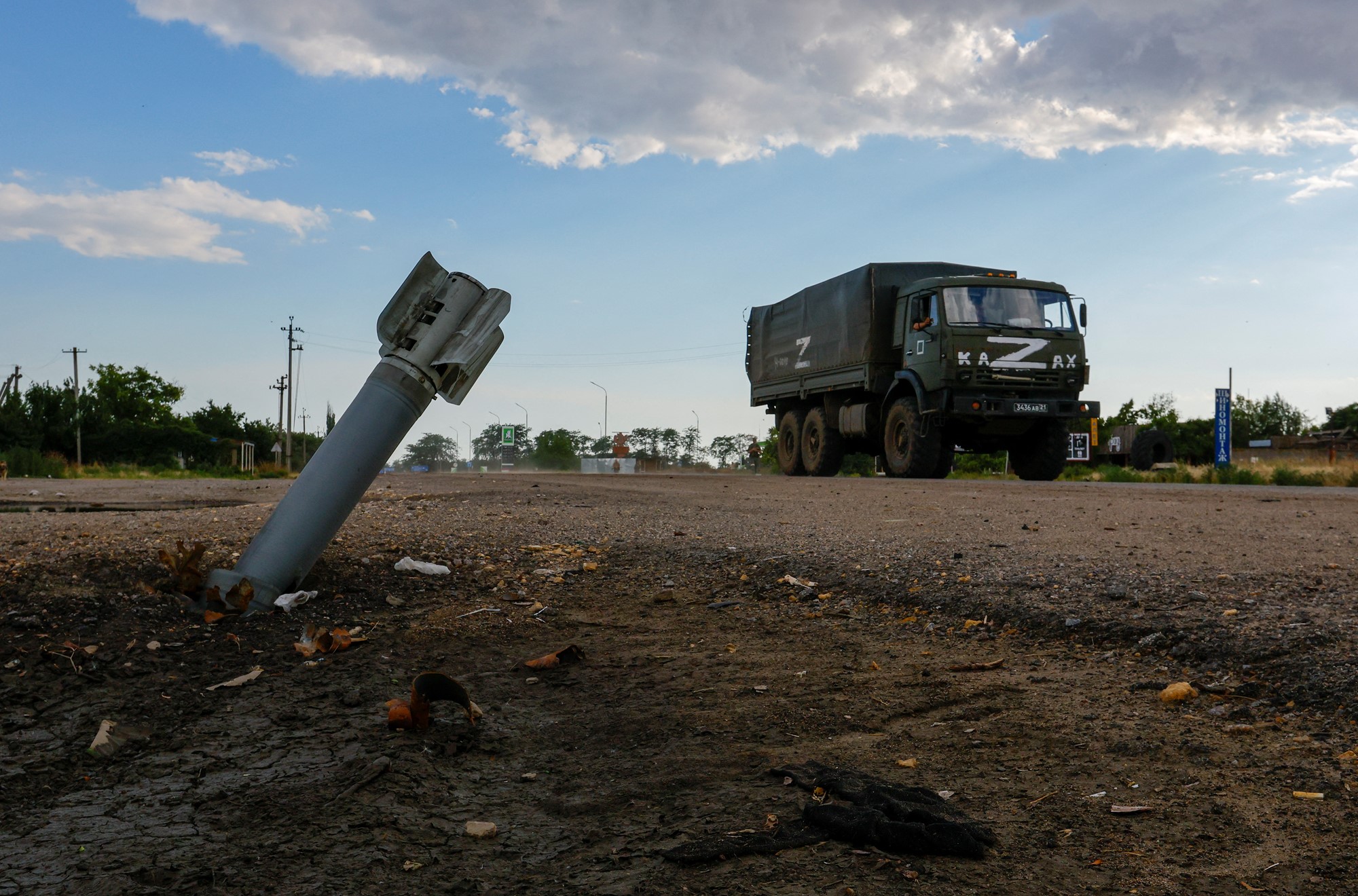 A Russian military truck drives past an unexploded munition during Ukraine-Russia conflict